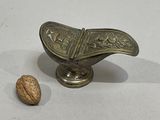 a small metal object with a walnut in it