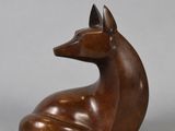 a bronze sculpture of a dog sitting on a gray surface