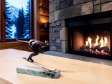 a statue of a bird sitting on a table in front of a fireplace