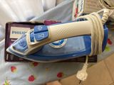 a blue and white iron sitting on a bed next to a book