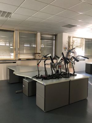 une salle où se trouvent plusieurs bureaux et chaises