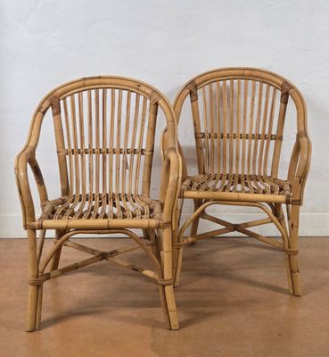 pair of rattan chairs with arms and backrests in natural wood