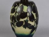 a black and green vase with leaves painted on it