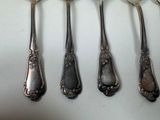 five spoons and a fork on a white surface