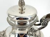 a silver tea pot with a handle and a lid