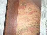 an old book with a brown cover on a bed