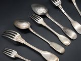 six silver spoons and a fork on a black surface
