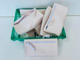un panier vert rempli de sacs à main blancs posé sur une table blanche
