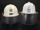 pair of white hard hats with face shields on a black background