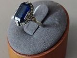 a ring with a blue stone in it sitting on a wooden box