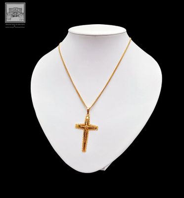 a gold necklace with a cross on a mannequin neck