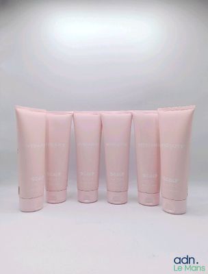 quatre tubes de lotion rose posés les uns à côté des autres sur une surface blanche