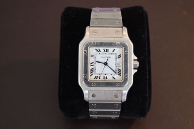 a silver watch with roman numerals on a black velvet band