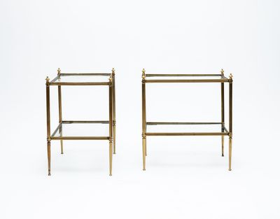 a pair of brass side tables with glass shelves