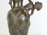 un vase en bronze sur lequel est représenté un enfant