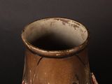 a brown vase sitting on a table with a black background