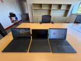 trois ordinateurs portables posés sur une table dans une pièce
