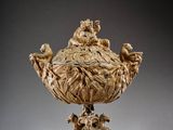 an ornately carved bowl with figures on it on a stand