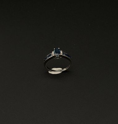 une photo d'une bague sertie d'un diamant et d'un saphir sur un fond noir