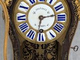 a clock that is sitting on a stand with a blue and gold decoration