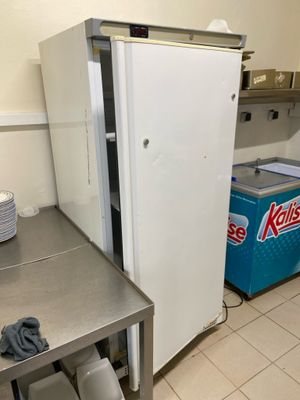 un réfrigérateur qui se trouve dans une cuisine, à côté d'une table