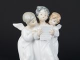trois figurines d'anges tenant une feuille de papier sur fond noir