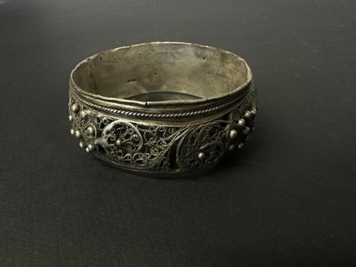 gros plan d'un bracelet en argent sur une surface noire