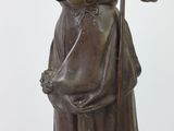 bronze statue of a woman with a cane and a hat
