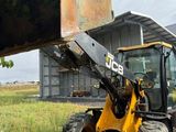 a backhoe of a tractor that is parked in the grass