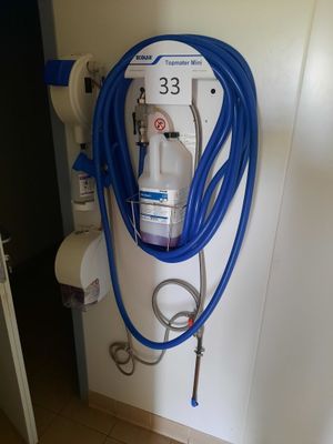 un tuyau bleu fixé à un mur blanc, à côté des toilettes