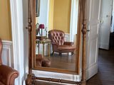 une photo d'un salon avec un fauteuil et un grand miroir