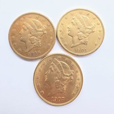 trois pièces d'or superposées sur une surface blanche