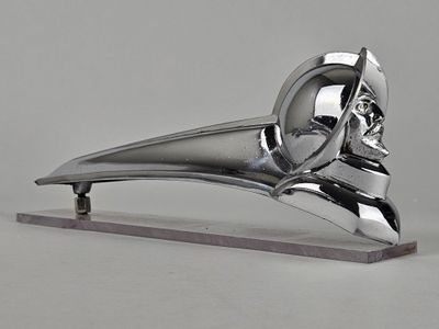 une sculpture en argent représentant un oiseau, posée sur un socle