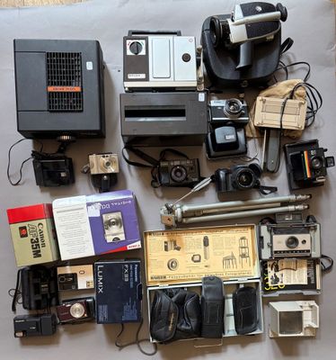 beaucoup de vieux appareils photo et d'autres appareils électroniques posés sur une table