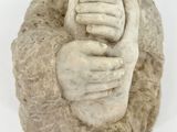 une statue représentant deux mains qui se tiennent l'une l'autre sur un rocher