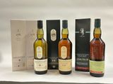 trois bouteilles de whisky et une boîte de vin posées sur une table