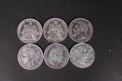 six pièces d'argent de tailles et de formes différentes sur une surface noire