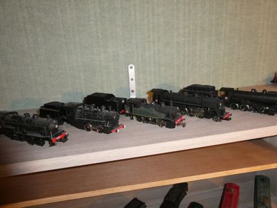 several toy trains are lined up on a shelf in front of a wall