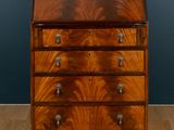 an antique walnut bureau with three drawers on casteors