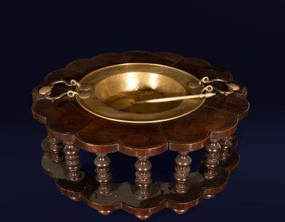 a gold plate on a wooden stand with a spoon in it