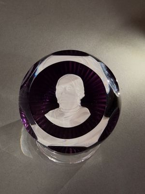 un presse-papier en verre violet sur lequel est représenté un homme