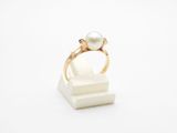 une bague en perle et en or posée sur un bloc de marbre blanc