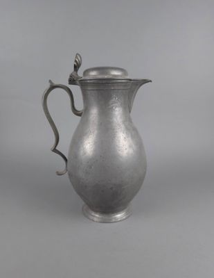 un pichet ancien en argent muni d'une anse, sur fond gris