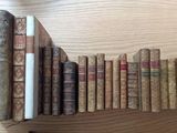 many old books lined up on a shelf on a table