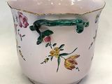 a vase with a handle and flowers painted on it