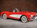 an old red and white car parked in front of a brick wall