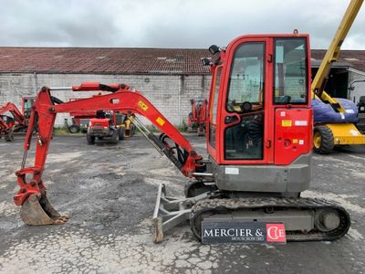 a red excavator that is parked in a parking lot