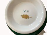 a white bowl with a green rim and a yellow bird on it