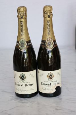 two bottles of wine sitting on top of a counter next to a bottle of wine