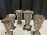 Plusieurs vases en argent sont posés sur une table blanche.